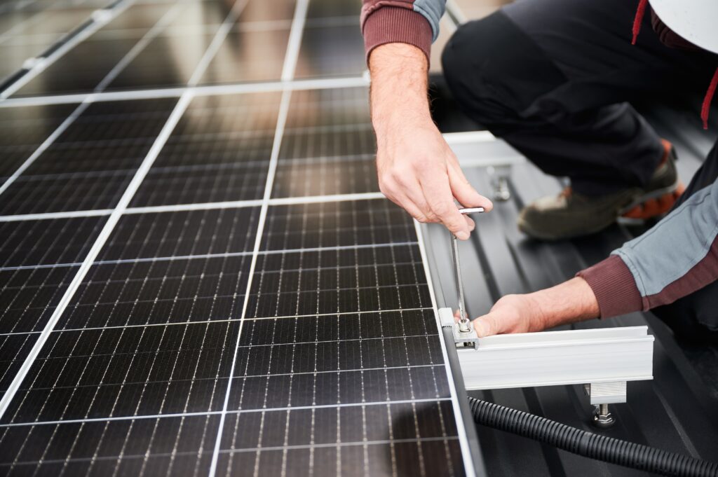 Man,Electrician,Mounting,Photovoltaic,Solar,Panels,On,Roof,Of,House.